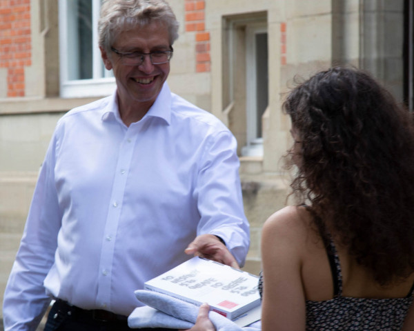 Stefan Grünenwald übergibt ein Buch an Absolventin